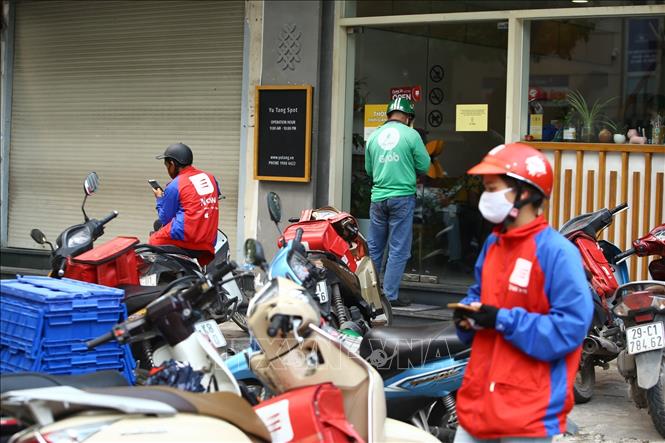 Trong ảnh: Nhiều shipper tập trung trước một cửa hàng, chuẩn bị nhận đơn giao cho khách. Ảnh: Minh Quyết - TTXVN