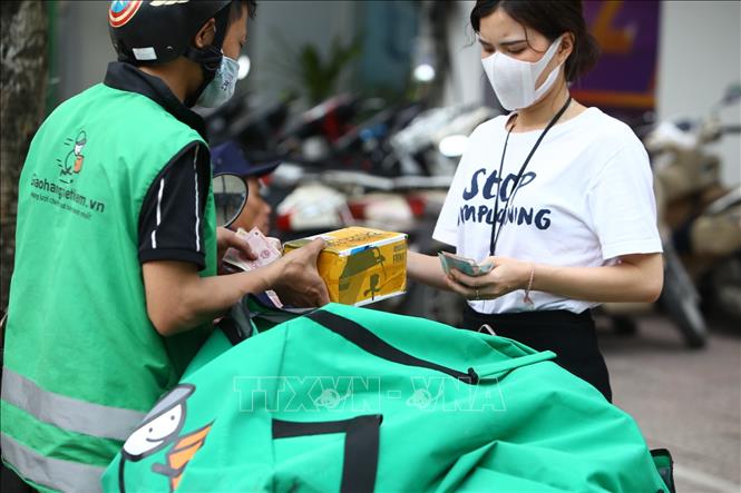 Trong ảnh: Shipper giao hàng cho khách. Ảnh: Minh Quyết - TTXVN