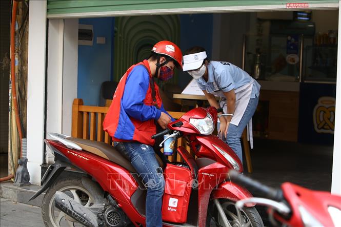 Trong ảnh: Gần như các của hàng chỉ mở cửa đủ để chờ shipper đến nhận đơn. Ảnh: Minh Quyết - TTXVN