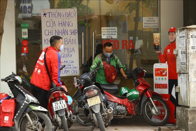 Trong ảnh: Nhiều cửa hàng hạn chế bán hàng trực tiếp cho khách, chỉ bán hàng thông qua dịch vụ shiper. Ảnh: Minh Quyết - TTXVN