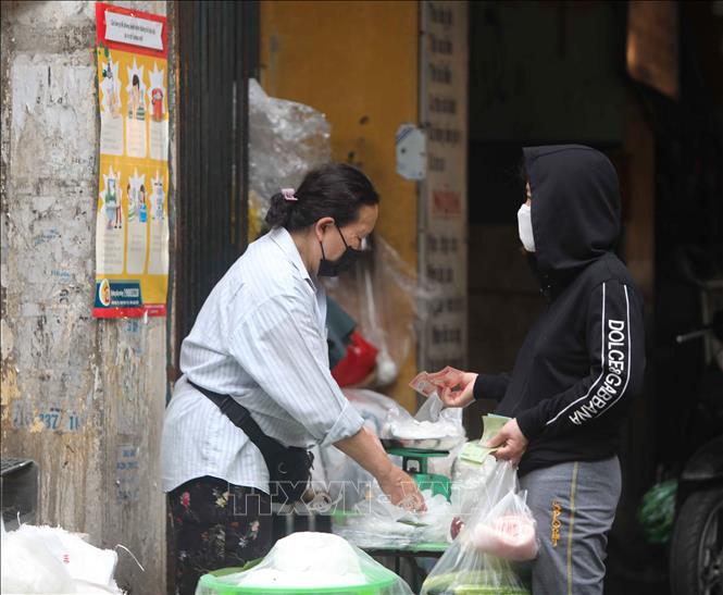 Trong ảnh: Cả người bán và người mua đều đeo khẩu trang để phòng, chống dịch. Ảnh: Thanh Tùng-TTXVN