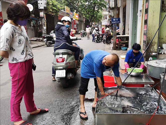 Trong ảnh: Vẫn còn những người bán hàng không thực hiện đeo khẩu trang khi tiếp xúc với người mua. Ảnh: Thanh Tùng-TTXVN