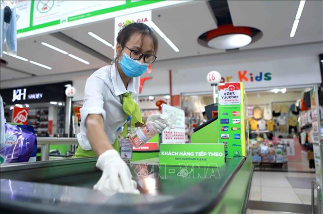 Trong ảnh: Nhân viên thu ngân Trung tâm thương mại Bic C Vĩnh Phúc đeo khẩu trang, găng tay cao su, và vệ sinh khu vực làm việc hàng ngày. Ảnh: Hoàng Hùng -TTXVN