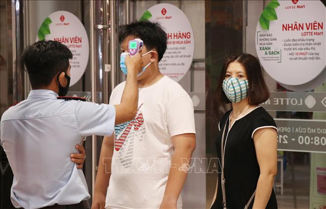 Trong ảnh: Kiểm tra thân nhiệt trước khi vào siêu thị Lotte Mart, Nha Trang. Ảnh: Tiên Minh - TTXVN