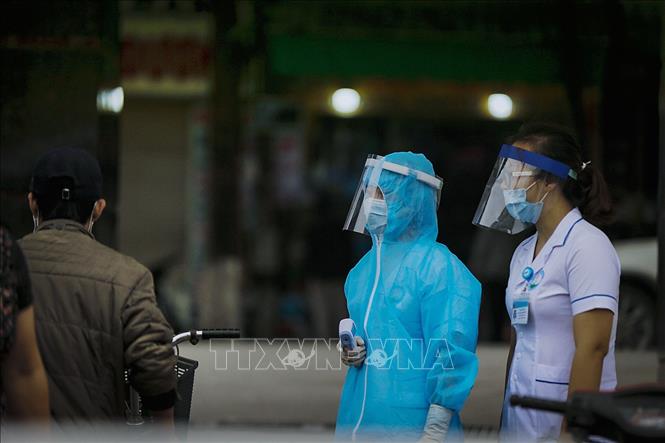 Trong ảnh: Lực lượng chốt bảo vệ đo thân nhiệt và khai báo ngay phía cổng bệnh viện cũng đang sử dụng chiếc mũ mà chị Vũ Thị Hoa làm ra. Ảnh: Trọng Đạt - TTXVN