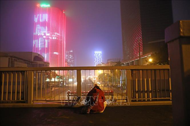 Trong ảnh: Một người dân ngồi trên cầu vượt đi bộ đường Láng Hạ, giữa khung cảnh đường phố vắng người. Ảnh: Huy Hùng - TTXVN
