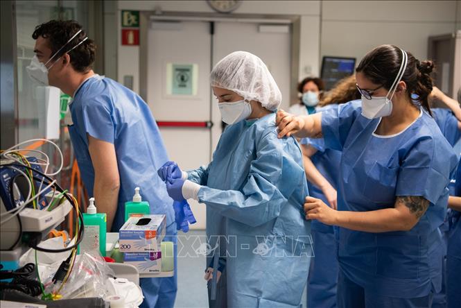 Trong ảnh: Nhân viên y tế hỗ trợ nhau mặc đồ bảo hộ trước khi tới khu điều trị cho bệnh nhân nhiễm COVID-19 tại bệnh viện ở Barcelona, Tây Ban Nha ngày 20/3/2020. Ảnh: THX/TTXVN