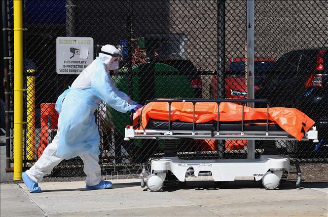 Trong ảnh: Nhân viên y tế chuyển thi thể bệnh nhân nhiễm COVID-19 tới nhà xác dã chiến bên ngoài bệnh viện ở Brooklyn, New York (Mỹ) ngày 2/4/2020. Ảnh: AFP/TTXVN