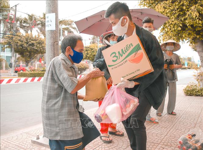 Trong ảnh: Anh Nguyễn Trí Ngân (huyện Tam Bình) trao quà cho người bán vé số dạo. Ảnh: Lê Thúy Hằng-TTXVN