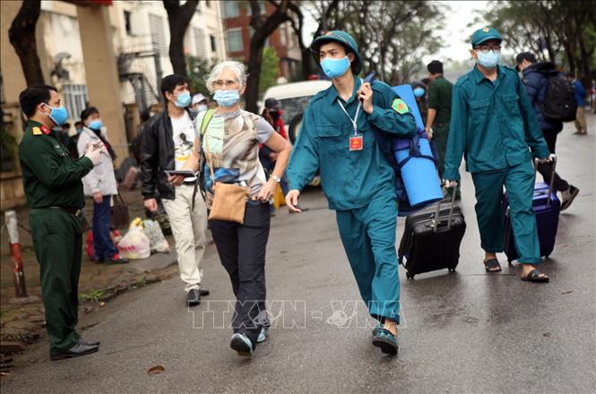 Trong ảnh: Lực lượng dân quân tự vệ quận Hoàng Mai giúp đỡ một người nước ngoài hoàn thành cách ly mang hành lý ra xe. Ảnh: Danh Lam – TTXVN