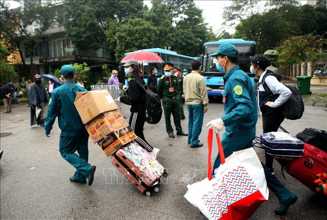 Trong ảnh: Lực lượng dân quân tự vệ quận Hoàng Mai giúp đỡ người hoàn thành cách ly mang hành lý ra xe. Ảnh: Danh Lam – TTXVN