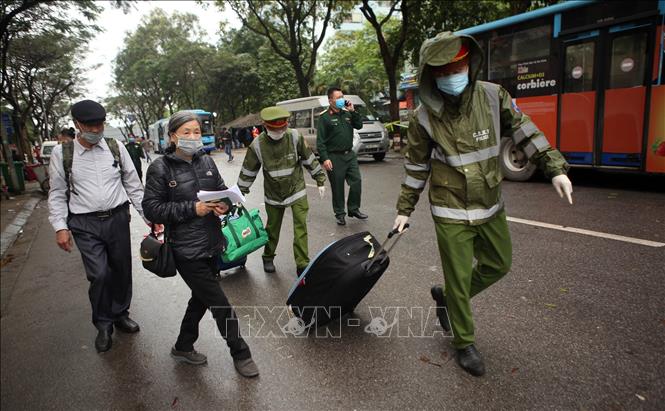 Trong ảnh: Công an quận Hoàng Mai giúp đỡ người hoàn thành cách ly mang hành lý ra xe. Ảnh: Danh Lam – TTXVN