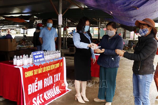 Trong ảnh: Thực hiện rửa tay sát khuẩn cho người dân tại chợ trung tâm thị trấn Tằng Loỏng. Ảnh: Quốc Khánh - TTXVN