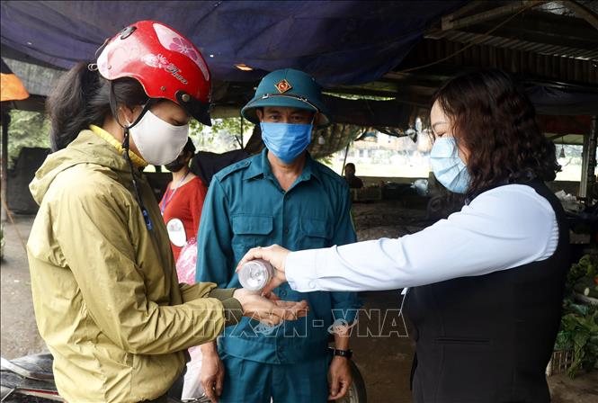 Trong ảnh: Thực hiện rửa tay sát khuẩn cho người dân tại  tại chợ trung tâm thị trấn Tằng Loỏng. Ảnh: Quốc Khánh - TTXVN