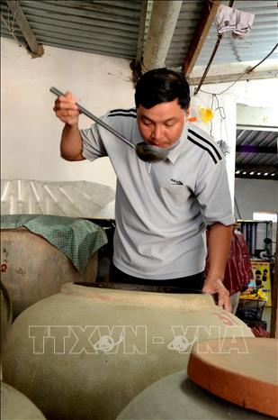 Photo: Checking fish sauce at Huong Lang Co (ancient village’s taste) establishment in Nam O village. VNA Photo: Quốc Dũng