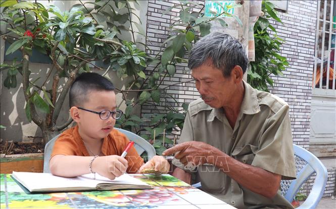 Trong ảnh: Niềm vui bên cháu ngoại của ông Nguyễn Ngọc Đức sau giờ vớt rác. Ảnh: Xuân Khu-TTXVN