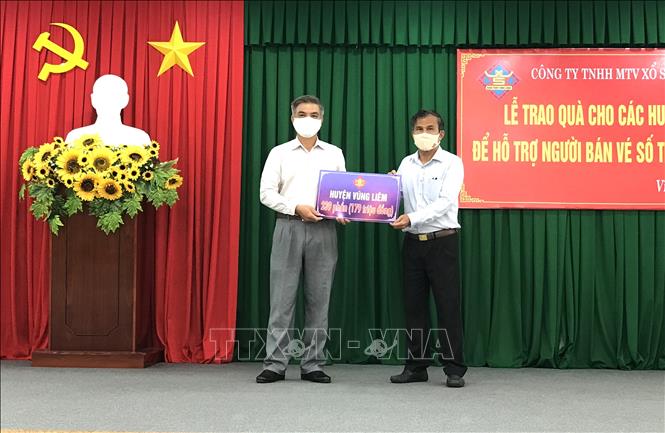 Trong ảnh: Giám đốc Công ty TNHH Một thành viên Xổ số kiến thiết Vĩnh Long Thiệu Ngọc Tâm (bên phải) trao tiền hỗ trợ cho các địa phương. Ảnh: Lê Thúy Hằng - TTXVN