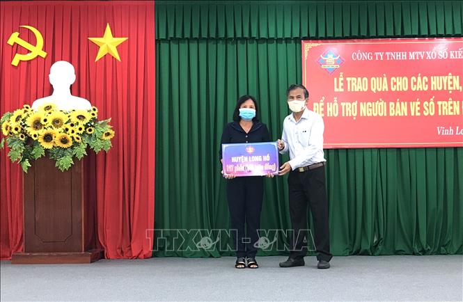 Trong ảnh: Giám đốc Công ty TNHH Một thành viên Xổ số kiến thiết Vĩnh Long Thiệu Ngọc Tâm (bên phải) trao số tiền hỗ trợ cho các địa phương. Ảnh: Lê Thúy Hằng - TTXVN