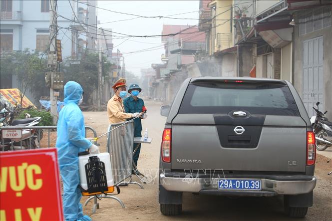 Trong ảnh: Kiểm soát chặt chẽ, phun khử khuẩn xe ra vào khu vực xã Dũng Tiến. Ảnh: Minh Quyết - TTXVN