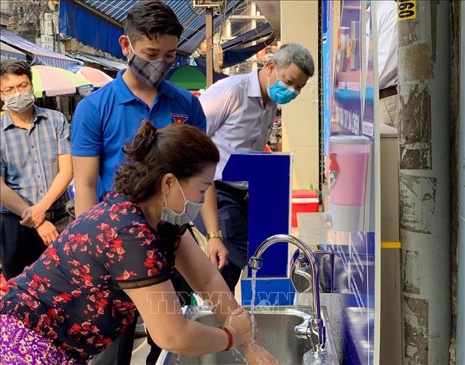 Trong ảnh: Hướng dẫn người dân sử dụng trạm rửa tay dã chiến tại chợ Cố Đạo, quận Ngô Quyền, thành phố Hải Phòng. Ảnh: TTXVN