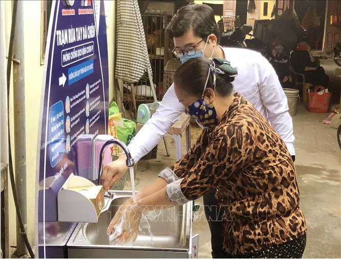 Trong ảnh: Hướng dẫn người dân rửa tay tại trạm rửa tay dã chiến. Ảnh: TTXVN