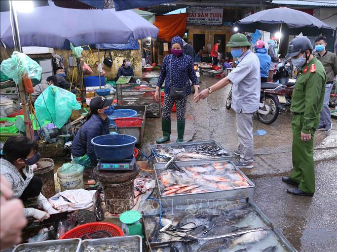 Trong ảnh: Lực lượng chức năng của phường Minh Khai tổ chức tuyên truyền nhắc nhở các tiểu thương và người dân đến mua sắm tại chợ đầu mối Minh Khai chấp hành tốt  chỉ thị số 16/CT-TTg. Ảnh: Vũ Sinh - TTXVN