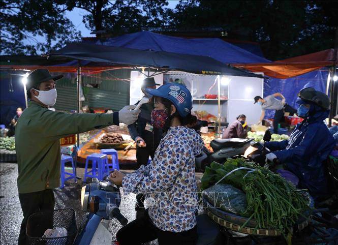 Trong ảnh: Các lực lượng chức năng của phường Minh Khai, quận Bắc Từ Liêm tổ chức thực hiện công tác phòng bệnh cho tất cả mọi người ra vào chợ. Ảnh: Vũ Sinh - TTXVN