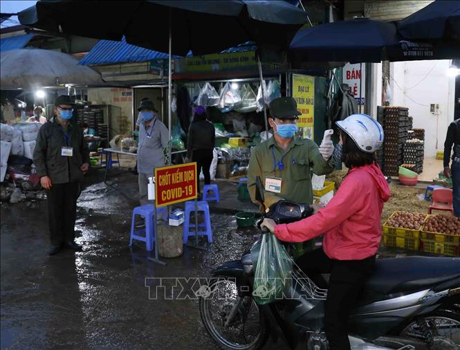 Trong ảnh: Các lực lượng chức năng của phường Minh Khai, quận Bắc Từ Liêm tổ chức thực hiện công tác phòng bệnh cho tất cả mọi người ra vào chợ. Ảnh: Vũ Sinh - TTXVN