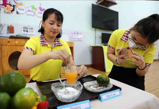 Trong ảnh: Giáo viên Trường Mầm non Thanh Xuân Trung làm bài giảng trực tuyến, hướng dẫn trẻ pha nước cam đồng thời nhắn nhủ các con ăn nhiều hoa quả để tăng sức đề kháng. Ảnh: Thanh Tùng - TTXVN