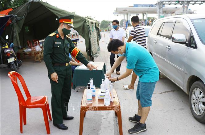 Trong ảnh: Người dân rửa tay khử trùng trước khi khai báo y tế với lực lượng chức năng. Ảnh: Đinh Tuấn - TTXVN
