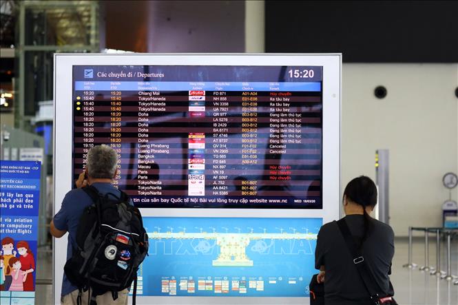 Trong ảnh: Hai hành khách xem thông tin chuyến bay tại sân bay quốc tế Nội Bài. Ảnh: Huy Hùng - TTXVN