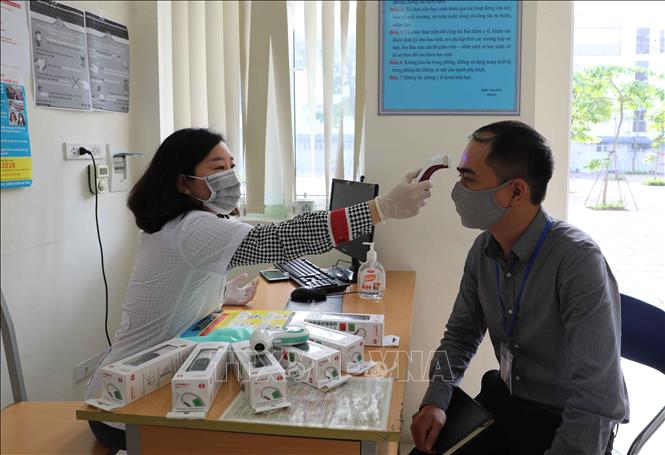 Trong ảnh: Nhân viên y tế Trường THCS Phan Chu Trinh, quận Ba Đình kiểm tra hoạt động của thiết bị đo thân nhiệt để đưa vào sử dụng khi học sinh đi học trở lại. Ảnh: Thanh Tùng - TTXVN