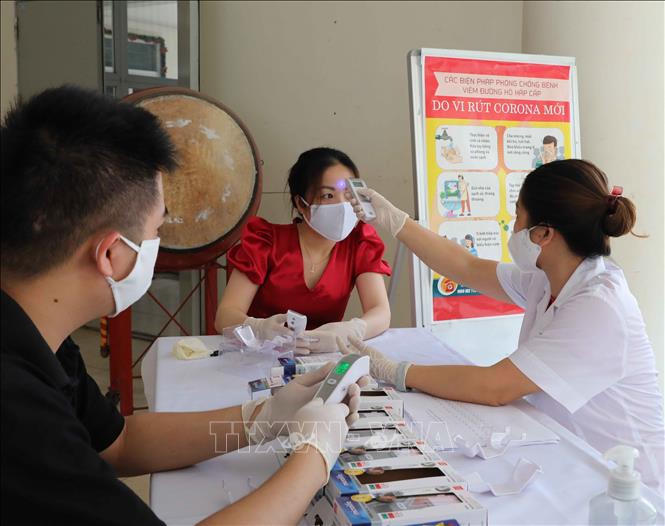 Trong ảnh: Nhân viên y tế Trường THCS Mạc Đĩnh Chi, quận Ba Đình kiểm tra, hướng dẫn giáo viên sử dụng thiết bị đo thân nhiệt đúng cách. Ảnh: Thanh Tùng - TTXVN