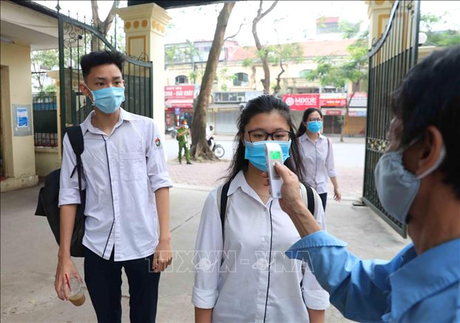 Trong ảnh: Học sinh trường THPT Việt Đức, quận Hoàn Kiếm được đo kiểm tra thân nhiệt trước khi vào trường theo đúng quy định. Ảnh: Thành Đạt - TTXVN