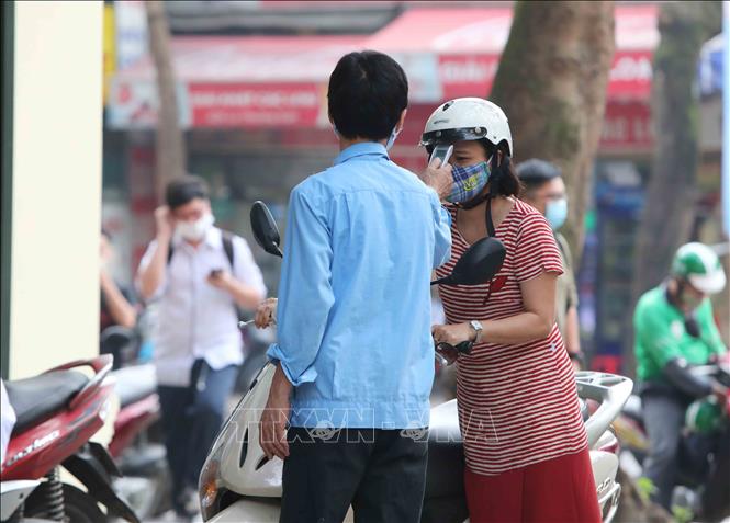 Trong ảnh: Tất cả giáo viên và học sinh đều được đo kiểm tra thân nhiệt trước khi vào trường theo đúng quy định. Ảnh: Thành Đạt - TTXVN