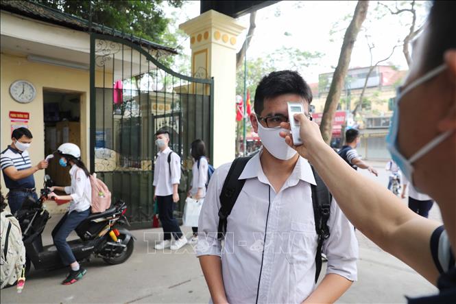 Trong ảnh: Tất cả giáo viên và học sinh đều được đo kiểm tra thân nhiệt trước khi vào trường theo đúng quy định. Ảnh: Thành Đạt - TTXVN