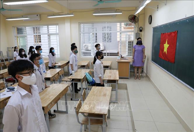 Trong ảnh: Học sinh Trường THPT Trần Nhân Tông, quận Hai Bà Trưng chào cờ đầu tuần trong lớp học, đảm bảo giãn cách tối thiểu. Ảnh: Thanh Tùng - TTXVN