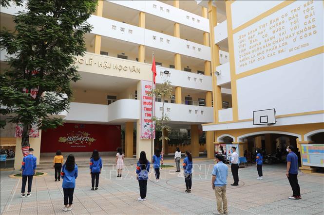 Trong ảnh: Giáo viên trường THPT Trần Nhân Tông, quận Hai Bà Trưng chào cờ đầu tuần đảm bảo giãn cách tối thiểu. Ảnh: Thanh Tùng - TTXVN