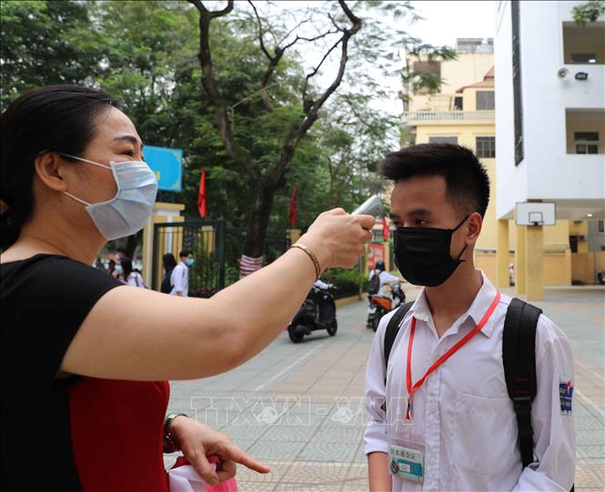 Trong ảnh: Kiểm tra thân nhiệt cho học sinh ngay khi vào cổng trường. Ảnh: Thanh Tùng - TTXVN