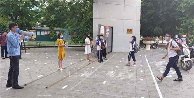Trong ảnh: Học sinh trường THCS Dịch Vọng, quận Cầu Giấy trở lại học từ sáng 4/5 được kiểm tra thân nhiệt, hướng dẫn di chuyển đảm bảo giãn cách. Ảnh: Nguyễn Cúc - TTXVN