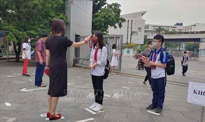 Trong ảnh: Học sinh trường THCS Dịch Vọng, quận Cầu Giấy trở lại học từ sáng 4/5 được kiểm tra thân nhiệt, hướng dẫn di chuyển đảm bảo giãn cách. Ảnh: Nguyễn Cúc - TTXVN