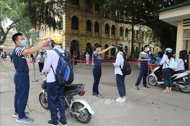 Trong ảnh: Các thầy cô giáo và bảo vệ trường THPT Việt Đức đảm bảo giãn cách, kiểm tra nhiệt độ cho học sinh trước khi vào trường. Ảnh: Thành Đạt - TTXVN