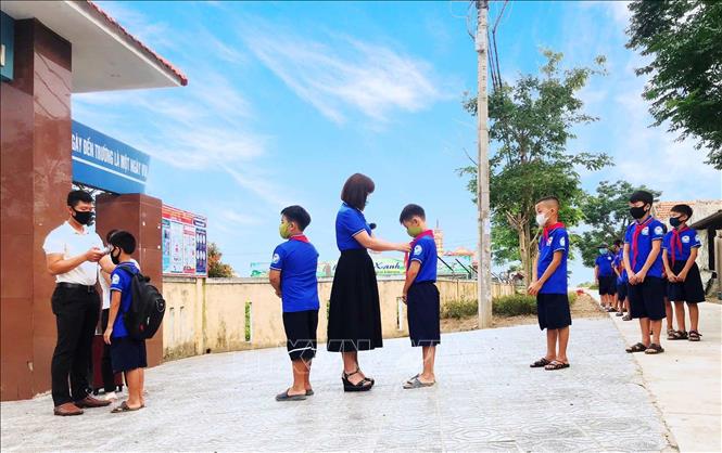 Trong ảnh: Thầy trò trường Tiểu học số 2 Quảng Văn (thị xã Ba Đồn, Quảng Bình) thực hiện nghiêm túc kiểm tra thân nhiệt và giữ khoảng cách. Ảnh: Võ Dung -TTXVN