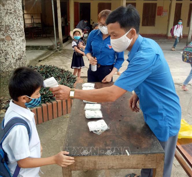 Trong ảnh: Đoàn viên, thanh niên huyện miền núi Như Thanh, tỉnh Thanh Hóa đo thân nhiệt, hướng dẫn học sinh rửa tay sát khuẩn phòng dịch COVID-19. Ảnh: Nguyễn Nam-TTXVN