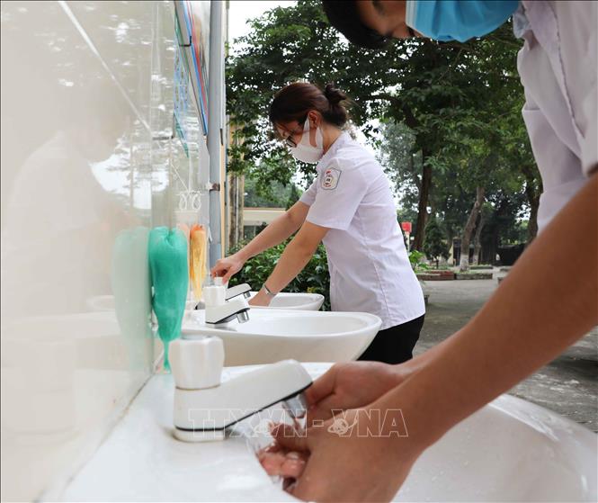 Photo: Students returning to school in Vietnam’s two largest metropolises have to undergo body temperature checks and sanitize their hands to prevent coronavirus. VNA Photo: Thanh Tùng