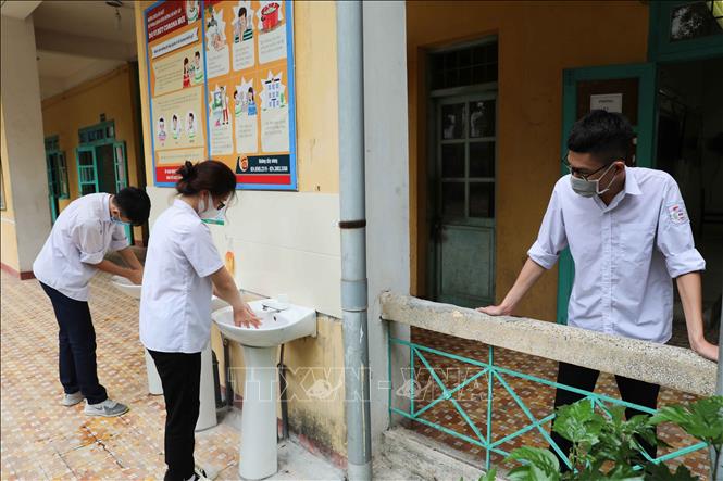 Photo: Students returning to school in Vietnam’s two largest metropolises have to undergo body temperature checks and sanitize their hands to prevent coronavirus. VNA Photo: Thanh Tùng