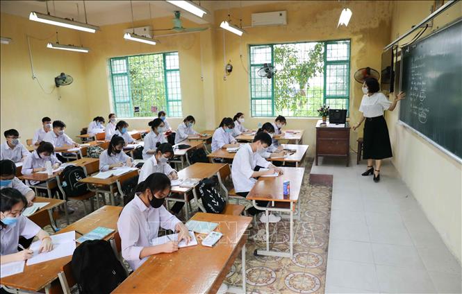 Photo: Students returning to school in Vietnam’s two largest metropolises have to undergo body temperature checks, sanitize their hands and only one student sits at one table, with each sitting at least a meter from each other to prevent the coronavirus. VNA Photo: Thanh Tùng