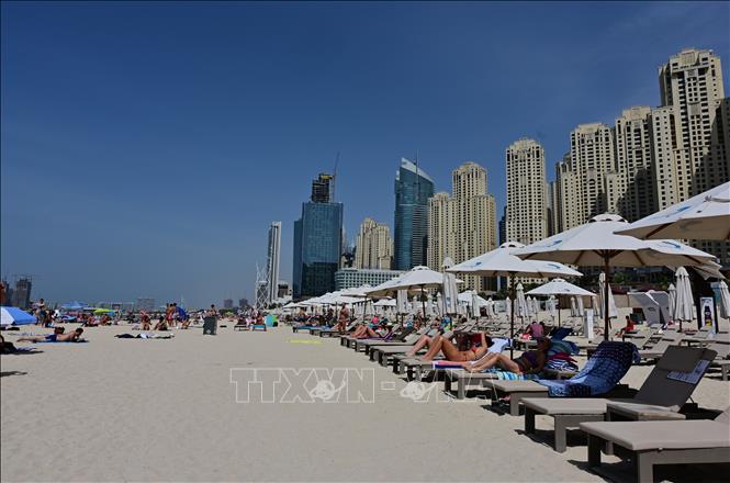 Trong ảnh: Người dân tắm nắng trên bãi biển ở Dubai, UAE, ngày 20/3/2020. Ảnh: AFP/TTXVN