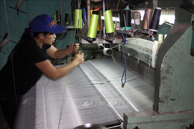 Trong ảnh: Công nhân Công ty TNHH tơ lụa Mã Châu ở thị trấn Nam Phước, huyện Duy Xuyên (tỉnh Quảng Nam) thực hiện một công đoạn trong quy trình sản xuất lụa. Ảnh: Trịnh Bang Nhiệm - TTXVN