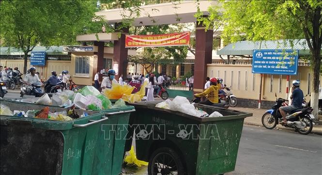 Trong ảnh: Nhiều xe thu gom rác thải tập kết ngay gần khu vực cổng trường học. Ảnh: Nam Thái - TTXVN